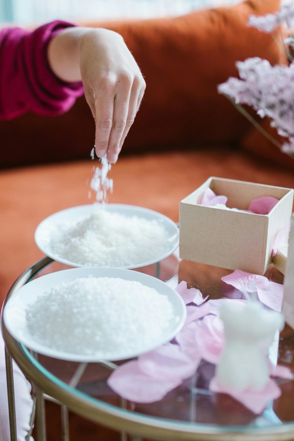 Close-up of hand crafting scented candles with floral petals and wax.